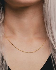 a woman with blonde hair wearing a gold necklace