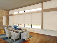 a dining room with wooden floors and large windows covered in shades of white blindes