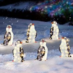 several penguins are standing in the snow with lights on their heads and feet, all facing different directions