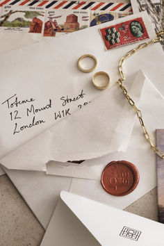 an envelope with a wax stamp and two wedding rings on it next to a penny