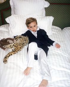 a young boy laying on top of a bed next to a stuffed cheetah