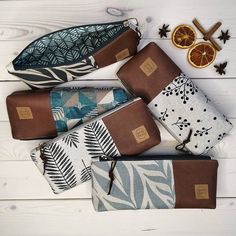 several different types of wallets on a white wooden table next to an orange slice