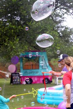 two children are playing with bubbles in an inflatable pool