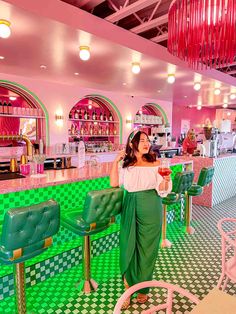 a woman standing in front of a green and white checkered floored bar area