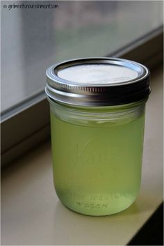 a glass jar filled with green liquid sitting on top of a window sill