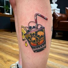 a tattoo on the leg of a person with a drink in it