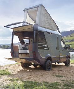 a camper van parked on the side of a body of water with its doors open