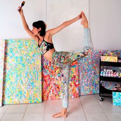 a woman doing a handstand in front of a wall with paint splattered on it