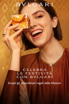 a woman is smiling and holding a small present in front of her face with the words bvlgari on it