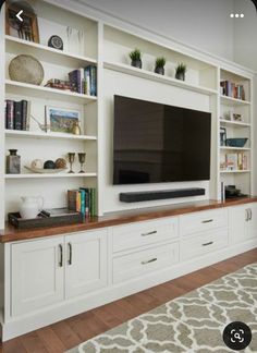 a flat screen tv sitting on top of a white bookcase in a living room