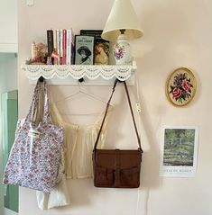 two purses are hanging on the wall next to a lamp and bookshelf