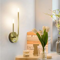 a vase filled with flowers sitting on top of a table next to a wall light