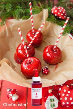 some red apples are sitting on a table with candy canes and christmas decorations in the background