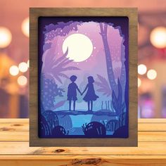 a wooden frame with an image of two people holding hands in front of a full moon