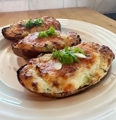 two baked potatoes on a white plate with green garnish