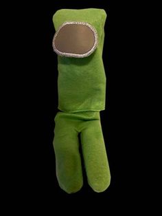 a green stuffed animal with a mirror on it's head and hands in the shape of a hand