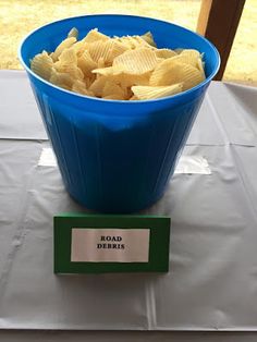 a blue bowl filled with potato chips sitting on top of a table next to a sign