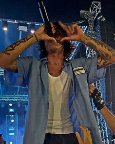 a man with long hair and tattoos on his arm holding a microphone up to his face