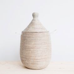 a large woven basket sitting on top of a wooden table next to a white wall