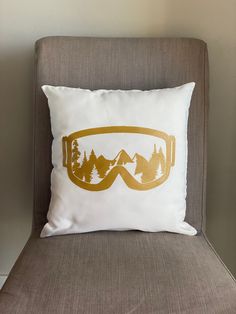 a pillow with an image of ski goggles on it sitting on a chair in front of a wall