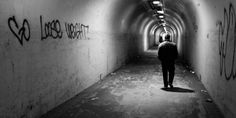 a man walking down a tunnel with graffiti on the walls