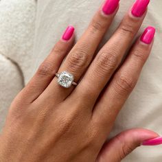 a woman's hand with pink nail polish and a diamond ring on her finger