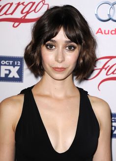 a woman with short brown hair wearing a black dress and posing for the camera at an event