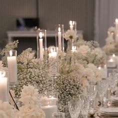 the table is set with candles, flowers and glass vases for centerpieces