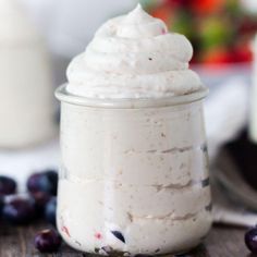 a glass jar filled with whipped cream surrounded by blueberries