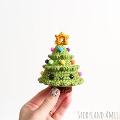 a crocheted christmas tree ornament being held by a woman's hand