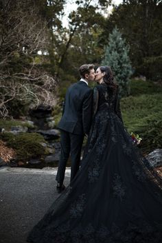 a man and woman dressed in black are kissing on the street while standing next to each other