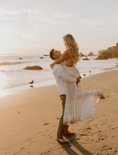 a man holding a woman on the beach