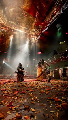 two people are dancing on the floor in front of bright lights and some leaves scattered around them