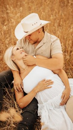 a man and woman cuddle in the middle of a field with tall brown grass