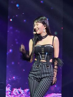 a woman standing on top of a stage wearing black and white striped pants with feathers