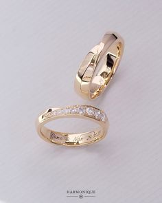 two gold wedding bands with diamonds on each one and the word love written in cursive writing