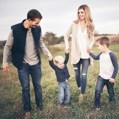 an adult and two children holding hands in a field