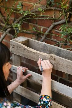 a woman is writing on a piece of wood