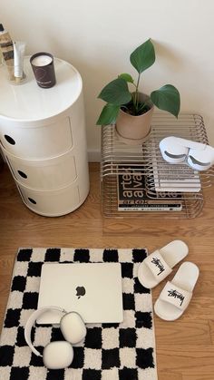 an apple laptop sitting on top of a black and white checkered rug next to a potted plant