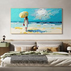 a woman with an umbrella is walking on the beach in front of a large painting