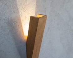 a light that is on the side of a wall next to a cement wall with a wooden post