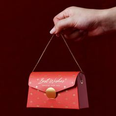 a woman's hand holding a red and gold envelope with a golden circle on it