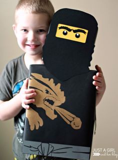 a young boy is holding up a cardboard ninja