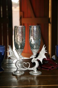 two wine glasses sitting on top of a table next to blue dishes and napkins