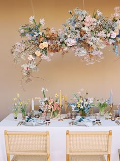 a table with flowers and candles is set up for a dinner or party in front of a wall