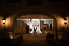 a bride and groom standing in front of the entrance to their wedding venue at night