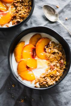 two bowls filled with yogurt and peaches on top of a gray table