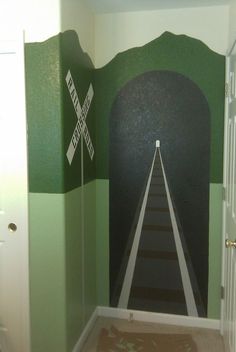 a hallway painted with green, white and black stripes leading to a tunnel in the wall