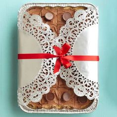 a box filled with cookies and chocolates on top of a table next to a red ribbon