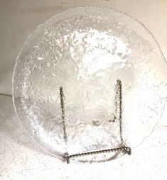 a clear glass plate sitting on top of a white tablecloth covered floor next to a wall